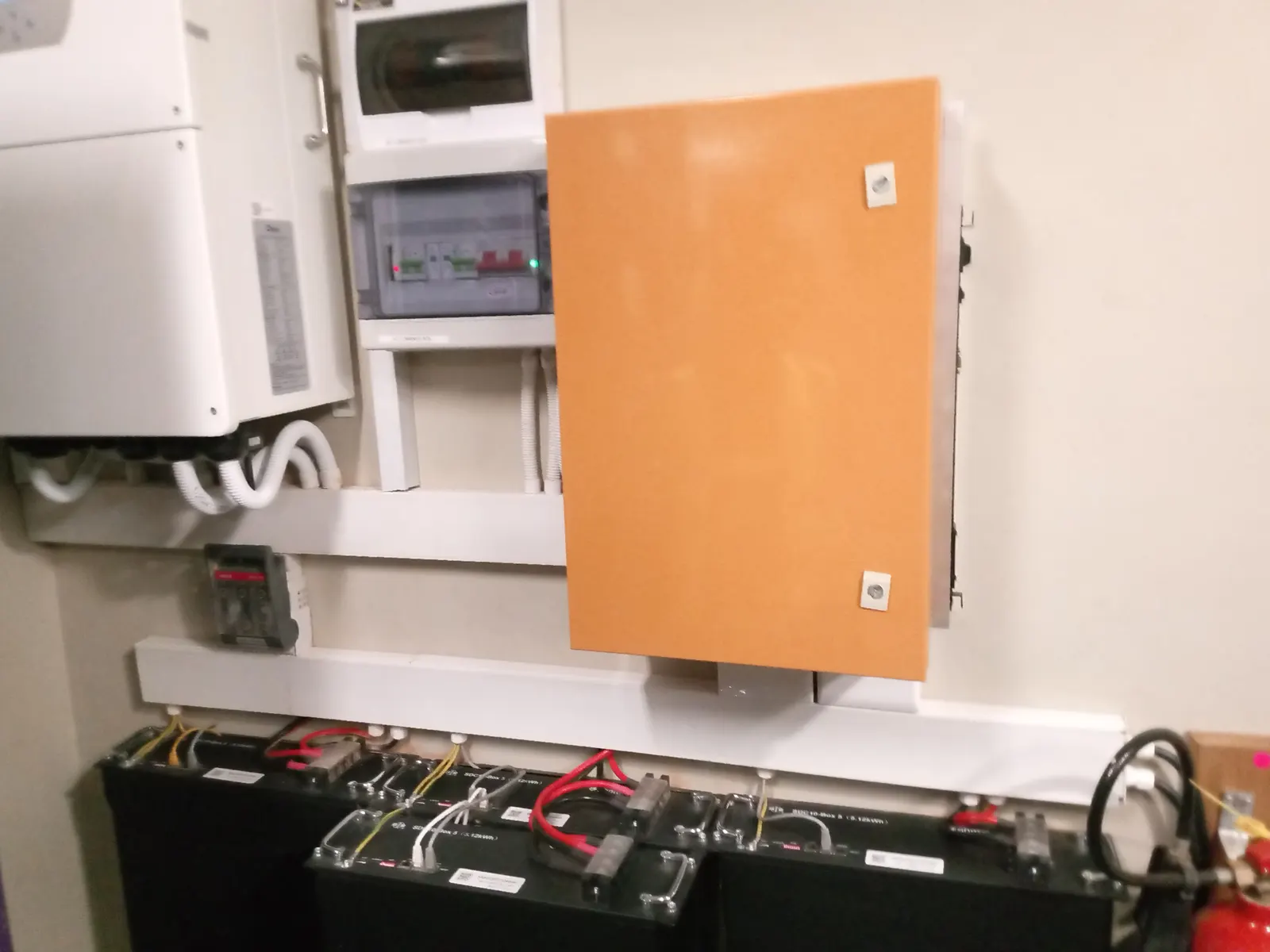 An inverter, a distribution board and a lockable changeover enclosure above a bank of batteries on a floor-mounted rack.