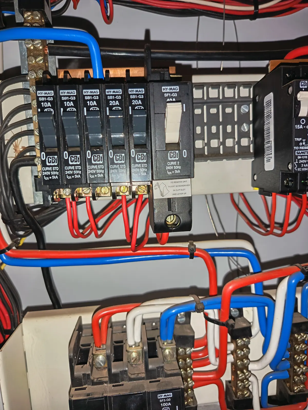 A panel build showing breakers, terminal blocks and colour-coded live, neutral and earth conductors run to a moulded-case breaker below.